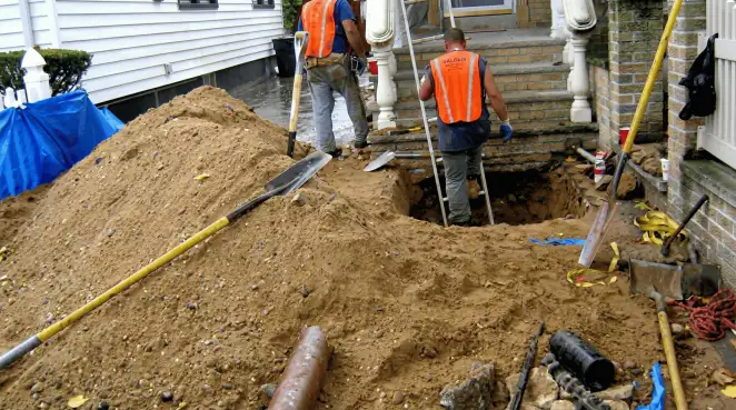 Contractors performing foundation protection and exterior drainage excavation near residential home steps in Columbia, MO
