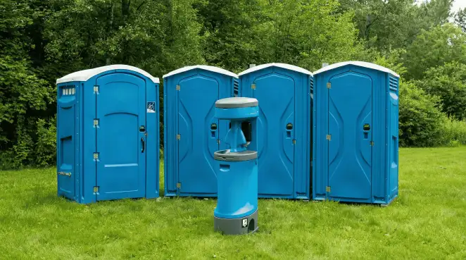 Four blue portable toilets and a matching hand washing station on grass near trees, a common sight at local outdoor events in Columbia, MO